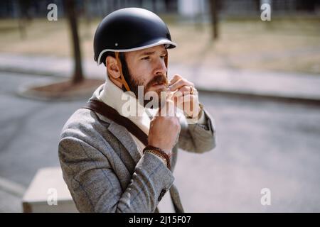 Gut aussehender Mann setzt sich vor der Fahrradtour einen Helm an. Sicherheit und umweltfreundlicher Transport Stockfoto