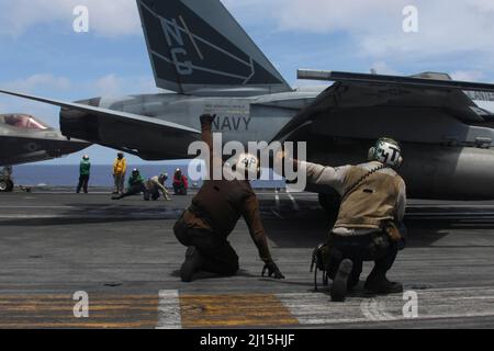 PHILIPPINISCHE SEEFAHRER (21. März 2022) signalisieren auf dem Flugdeck des Nimitz-Klasse-Flugzeugträgers USS Abraham Lincoln (CVN 72) eine F/A-18E Super Hornet, die den „Vigilanten“ des Strike Fighter Squadron (VFA) 151 zugewiesen wurde. Die Abraham Lincoln Strike Group befindet sich im geplanten Einsatzgebiet der US-Flotte für 7., um die Interoperabilität durch Allianzen und Partnerschaften zu verbessern und gleichzeitig als reaktionsfähige Truppe zur Unterstützung einer freien und offenen Region im Indo-Pazifik-Raum zu dienen. (USA Navy Foto von Mass Communication Specialist Seaman Apprentice Julia Brockman) Stockfoto