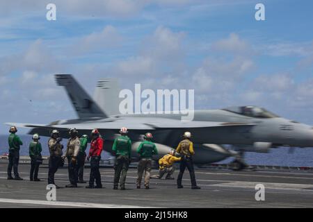 PHILIPPINISCHE SEE (21. März 2022) Seeleute beobachten den Flugbetrieb auf dem Flugdeck des Flugzeugträgers USS Abraham Lincoln (CVN 72) der Nimitz-Klasse. Die Abraham Lincoln Strike Group befindet sich im geplanten Einsatzgebiet der US-Flotte für 7., um die Interoperabilität durch Allianzen und Partnerschaften zu verbessern und gleichzeitig als reaktionsfähige Truppe zur Unterstützung einer freien und offenen Region im Indo-Pazifik-Raum zu dienen. (USA Navy Foto von Mass Communication Specialist Seaman Apprentice Julia Brockman) Stockfoto