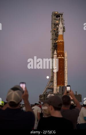 Der Mond steigt hinter der NASA-Rakete Space Launch System (SLS) mit der Orion-Sonde an Bord auf einem mobilen Trägerrakete auf, während er zum ersten Mal am Donnerstag, dem 17. März 2022, im Kennedy Space Center der NASA in Florida zum Launch Complex 39B ausrollt. Vor dem Artemis I-Flugtest der NASA werden die vollständig gestapelte und integrierte SLS-Rakete und die Orion-Raumsonde im Launch Complex 39B einer Nassprobe unterzogen, um die Systeme zu verifizieren und Countdown-Verfahren für den ersten Start zu üben. Bildnachweis: (NASA/Aubrey Gemignani) Stockfoto