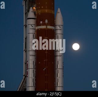 Der Mond steigt hinter der NASA-Rakete Space Launch System (SLS) mit der Orion-Sonde an Bord auf einem mobilen Trägerrakete auf, während er zum ersten Mal am Donnerstag, dem 17. März 2022, im Kennedy Space Center der NASA in Florida zum Launch Complex 39B ausrollt. Vor dem Artemis I-Flugtest der NASA werden die vollständig gestapelte und integrierte SLS-Rakete und die Orion-Raumsonde im Launch Complex 39B einer Nassprobe unterzogen, um die Systeme zu verifizieren und Countdown-Verfahren für den ersten Start zu üben. Bildnachweis: (NASA/Aubrey Gemignani) Stockfoto