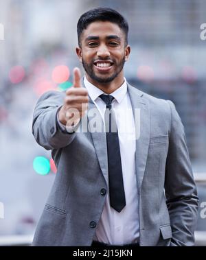 Ich habe es von hier aus abgedeckt. Aufnahme eines hübschen jungen Geschäftsmannes, der allein steht und den Daumen nach oben zeigt. Stockfoto
