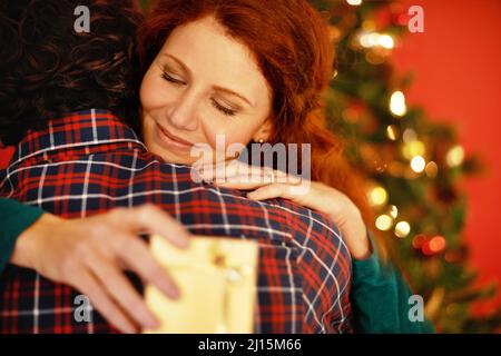 Dankbarkeit gegenüber dem Schenkenden. Aufnahme einer jungen Frau, die ihren Freund umarmt, nachdem sie ein Geschenk von ihm erhalten hatte. Stockfoto