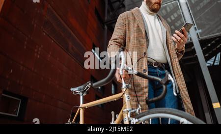 Mittelteil Detail der Hand mit dem Telefon. Geschäftsmann mit Mobiltelefon. Auf dem Weg zur Arbeit mit dem Fahrrad Stockfoto