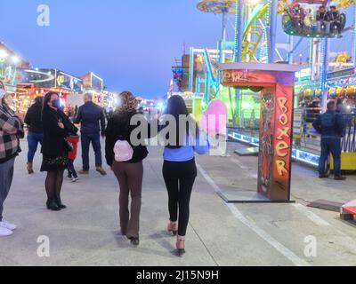 Zwei Frauen, die auf einem Abendmarkt spazieren gehen, während sie eine Zuckerwatte essen Stockfoto