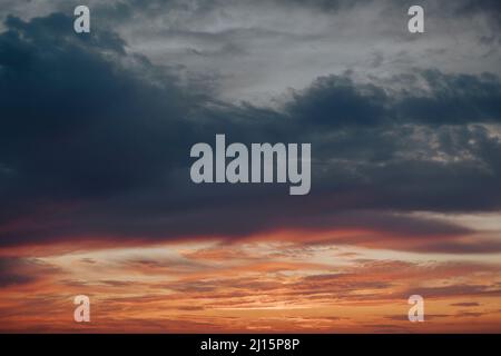 Dramatischer, wolkbedeckter Himmel bei schönem Sonnenuntergang, mit Tönen in Blau und Orange Stockfoto