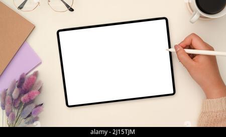 Aufnahme über dem Kopf, Zeichnung einer Frau auf einem digitalen Tablet-Touchpad in ihrem eleganten Arbeitsbereich. Modell mit weißem Bildschirm des Tablets. Stockfoto