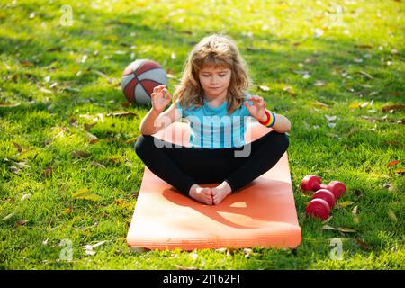 Portrait eines Kindes, das Yoga macht. Kleiner Junge, der in Lotushaltung meditiert. Gymnastik, Meditation für Kinder. Stockfoto