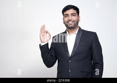 Porträt eines fröhlichen jungen Mannes, der eine gute Geste auf dem weißen, isolierten Hintergrund zeigt. Stockfoto