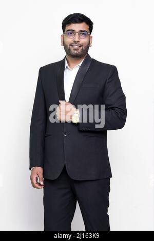 Junges elegantes Modell mit Anzug und Brillen, das die Kamera auf isoliertem Hintergrund anschaut. Stockfoto