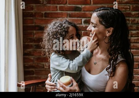 Mutter und Tochter, die zu Hause in Mexiko Lateinamerika Gesichtscreme oder Masken aufsetzen Stockfoto