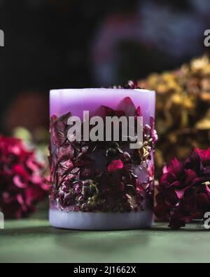 Handgemachte Kerzen mit einem einzigartigen Design, mit verschiedenen Blumen, trockenen Blättern auf einem hellen Hintergrund. Kerzen aus Bio-Wachs, Paraffin-Wachs. Entspannung Stockfoto