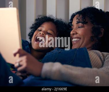 Vor dem Schlafengehen können Sie virtuelle Unterhaltung genießen. Aufnahme einer Frau und ihres Sohnes, die sich vor dem Schlafengehen etwas auf einem digitalen Tablet angeschaut haben. Stockfoto