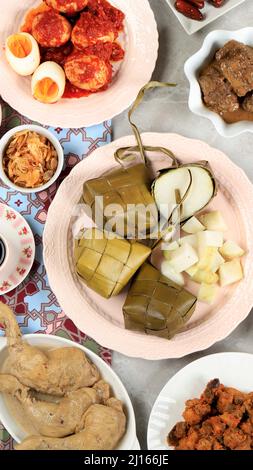 Ketupat Lebaran. Traditionelles festliches Gericht aus Reiskuchen oder Ketupat mit verschiedenen Beilagen, beliebt während der Eid-Feierlichkeiten. Für Social Med Stockfoto