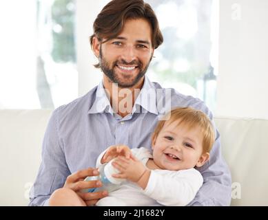 Wachsende Kinder brauchen viel Futter. Beschnittene Ansicht eines Vaters, der seinem jungen Sohn eine Flasche gab. Stockfoto