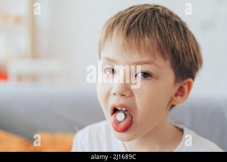 Junge mit weißer Pille auf der Zunge Stockfoto