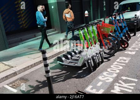 EScooter und Leihräder füllen einen Parkplatz, der für den Einsatz in der City of London, dem Finanzdistrikt der Hauptstadt, am 17.. März 2022 in London, England reserviert ist. Stockfoto