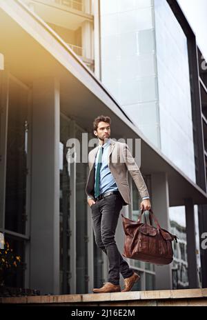 In einer großen Stadt braucht man großen Erfolg. Aufnahme eines hübschen und stilvollen jungen Geschäftsmannes in einer städtischen Umgebung. Stockfoto