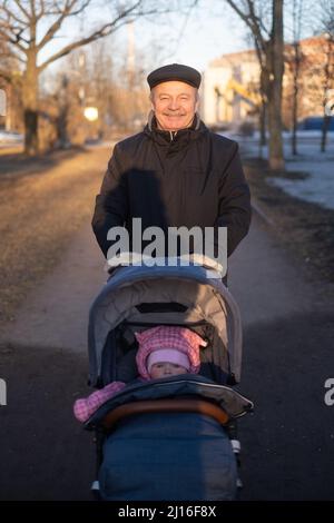 Großvater läuft mit einem Kinderwagen am verschneiten Wintertag Stockfoto