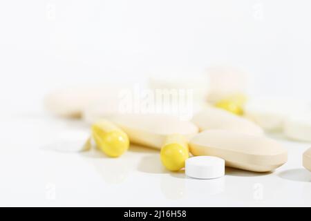 Tabletten und Kapseln in verschiedenen Formen und Größen auf weißem Hintergrund mit harten Schatten. Selektiver Fokus. Medizin und Drogen Konzept. Speicherplatz kopieren Stockfoto