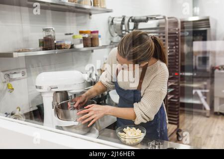 Frau, die in der großen Küche einen Mixer zum Mixen zusammenführt Stockfoto