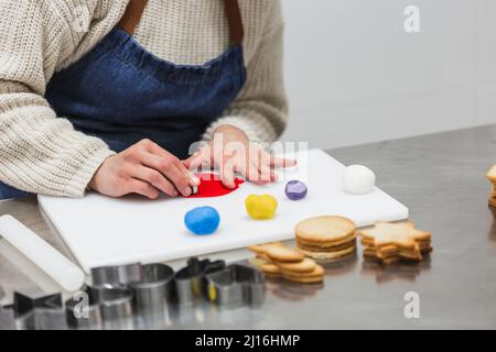 Crop Bäcker Schneiden bunte Gummipaste in der Bäckerei Stockfoto