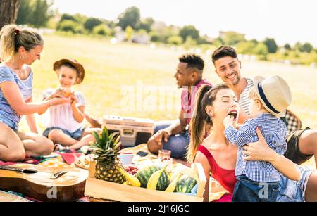 Glückliche multirassische Familien, die Spaß mit Kindern auf Picknick-Grillparty haben - multikulturelles Glück auf Freude und Liebe Konzept mit gemischten Rennen Menschen spielen Stockfoto