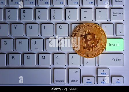 Glühender Bitcoin auf der Tastatur mit Text INVESTIEREN. Kryptowährung und Technologiekonzept. Stockfoto
