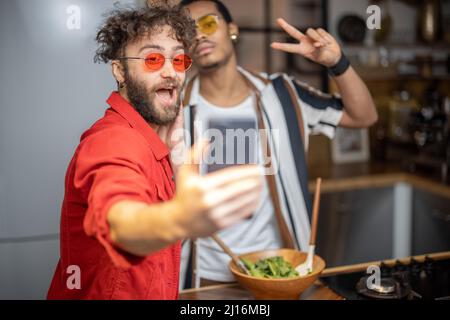 Zwei bunt gekleidete, stylische Jungs, die in Innenräumen Selfie am Telefon machen Stockfoto