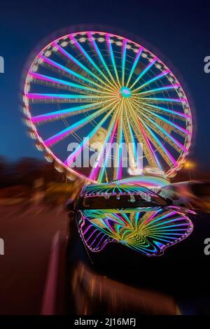 Riesiges, farbenfrohes Ferrisrad, das sich in einer blauen Sommernacht dreht Stockfoto