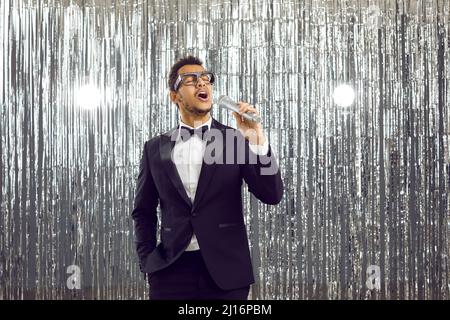 Junge schwarze Sängerin im Smoking-Anzug, die auf der Bühne steht, das Mikrofon hält und singt Stockfoto