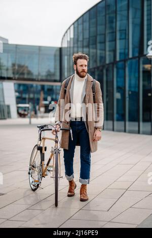 Junge Geschäftsführerin, die auf dem Fahrrad arbeitet. Umweltfreundlicher Transport. Vertikales Bild Stockfoto