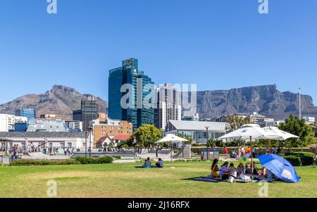 Kapstadt, Südafrika, 26.. Februar - 2022: Menschen picknicken auf Rasenflächen mit Stadt und Berg im Hintergrund. Stockfoto