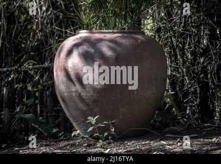 Alte große irdenen Glas oder große Vintage Tonglas für die Wasserspeicherung auf dem Boden im Garten mit viel grüner Baum Natur. Selektiver Fokus. Stockfoto