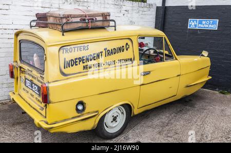 Yellow Reliant Robin Auto mit der einzigen Narren und Pferde Lackierung in schwarz lackiert.Trotters Independent Trading Co geparkt in Teddington Stockfoto