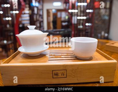 Gong Fu Cha brauen. Wunderschönes weißes Porzellan (Gaibei/Gaiwan & Teetasse) auf einem Bambustablett, perfekt für die Teeverkostung. Lock Cha Tea House, Hongkong Stockfoto