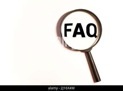 Lupe auf Holzbuchstaben als FAQ-Abkürzung, häufig gestellte Fragen auf Holzhintergrund. Stockfoto