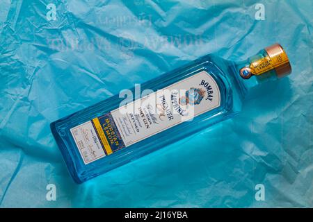 Flasche Bombay Sapphire Premier Cru destillierter London Dry Gin Vapor mit Murcian Lemon Hand ausgewählte exotische Botanicals auf blauem Seidenpapier Stockfoto