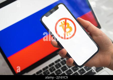 Poltava, Ukraine - 23. März 2022: Bitcoin und Kryptowährung in Russland verboten. Mobiltelefon mit Logo vor russischem Hintergrund Stockfoto