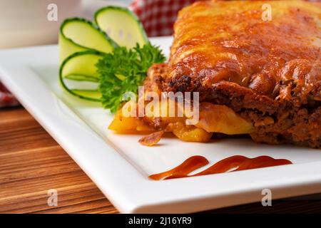 Leckere Lasagne auf dem Teller auf Holzboden serviert Stockfoto