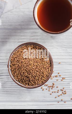 Schale mit Bockshornkleesamen und ägyptischem Bockshornkleesee oder Methi Dana Drink auf weißem Holzhintergrund Stockfoto