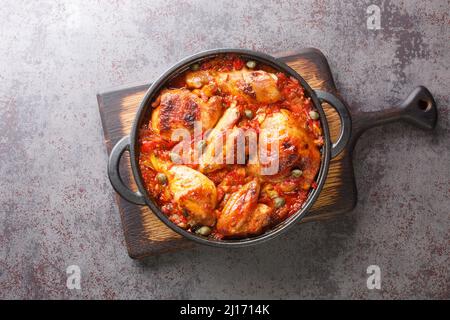 Spanische Küche Huhn mit Tomaten, Pfeffer, Zwiebel und Knoblauchsoße in einer Pfanne auf einem Schneidebrett gebacken. Horizontale Ansicht von oben Stockfoto