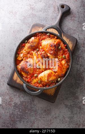 Gebackenes Hähnchen mit Sofrito-Gemüsesauce in einer Pfanne auf dem Tisch. Vertikale Draufsicht von oben Stockfoto