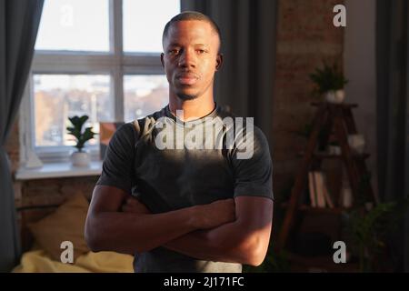 Horizontales mittleres Porträt eines modernen afroamerikanischen Mannes, der im Sonnenlicht Sportkleidung trägt Stockfoto
