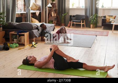 Horizontale Aufnahme von multiethnischen Männern und Frauen, die zu Hause eine Morgengymnastik machen Stockfoto