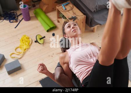 Horizontale Aufnahme aus einem hohen Winkel der jungen Frau, die während des morgendlichen Workouts auf dem Rücken ihrer Freunde balanciert Stockfoto