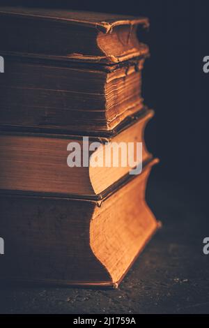 Stapel von Büchern mit antikem Leder vor dunklem Hintergrund Stockfoto