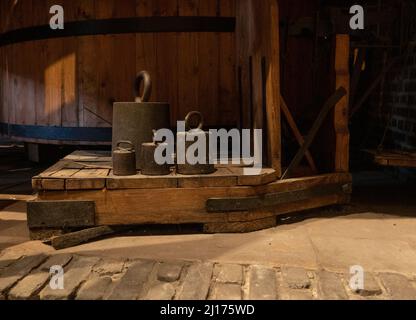 Alte Metallgewichte auf einer antiken Holzskala Stockfoto