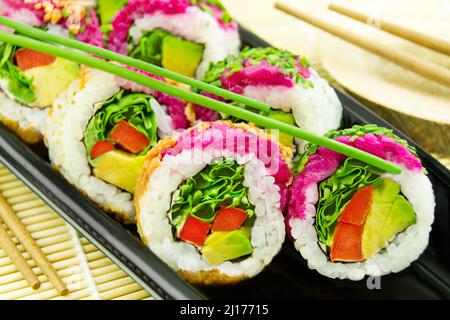Veggie Sushi California Roll und Essstäbchen auf Bambus Hintergrund Nahaufnahme Stockfoto
