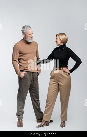 Positive stilvolle Frau umarmt Mann auf grauem Hintergrund Stockfoto